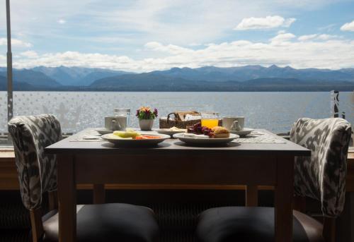 a table with food on it with a view of the water at Hotel Tres Reyes in San Carlos de Bariloche