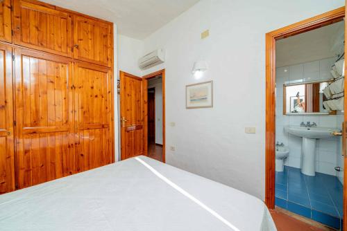 a bedroom with a bed and a bathroom with a sink at Villetta Cala D'Ambra in San Teodoro