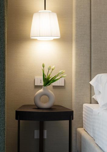 a vase of flowers on a table next to a bed at Ceccarini 9 home suite home in Riccione