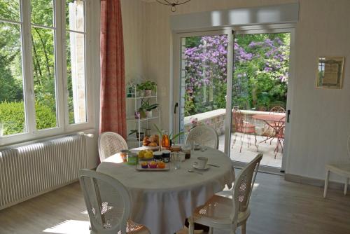 ein Esszimmer mit einem Tisch, Stühlen und einem Fenster in der Unterkunft Villa Matignon in Bagnoles de l'Orne