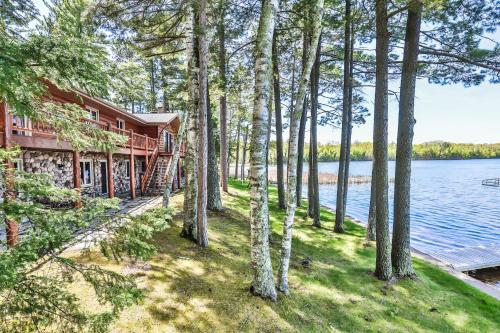 an exterior view of a house with trees and water at Whispering Pines Point in Boulder Junction