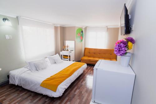a bedroom with a white bed and a couch at ApartaSuites & Hotel Bogota Suamox in Bogotá