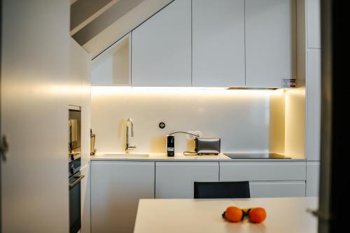 uma cozinha com armários brancos e laranjas numa mesa em Casa Guerreiro - Regina Hotel Group em Viana do Castelo