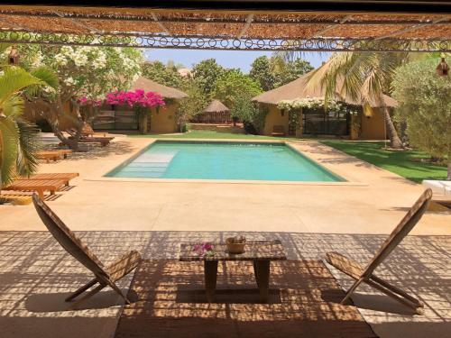 a pool with two chairs and a table in front of a house at Toubana Lodge in Ngaparou
