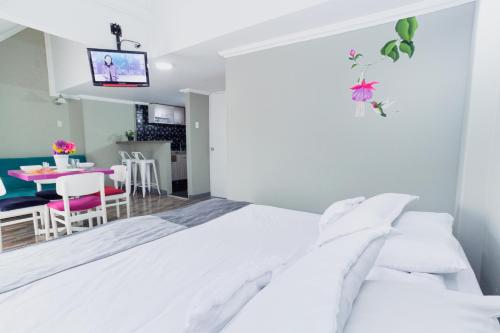 a bedroom with a white bed and a dining room at ApartaSuites & Hotel Bogota Suamox in Bogotá