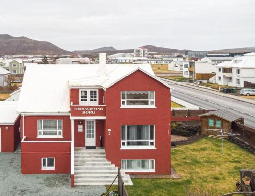 a red house with a white roof and a street at Grindavik Guesthouse self check in & out in Grindavík
