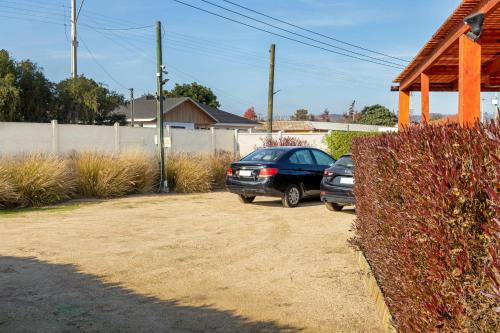 two cars parked in a parking lot next to a fence at Cabañas Rio Rapel in Rapel