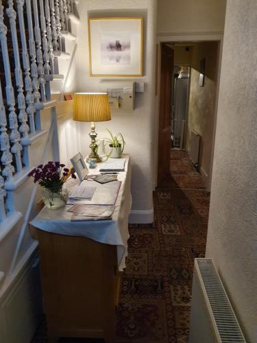 a hallway with a desk with a lamp and stairs at Strathallan B&B in Inverness
