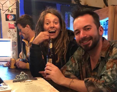 a man and a woman sitting at a table with a bottle at Fatima Hostel Bogotá in Bogotá