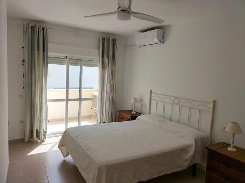 a white bedroom with a bed and a balcony at Comodidad en AGUAMARGA! in Agua Amarga