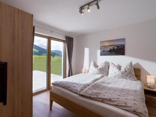 - une chambre avec un lit et une grande fenêtre dans l'établissement Reh4 Appartement, à Westendorf