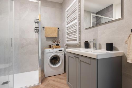 a bathroom with a washing machine and a sink at Glow Apartments, Aparthotel Kołłątaja - Wrzeszcz in Gdańsk