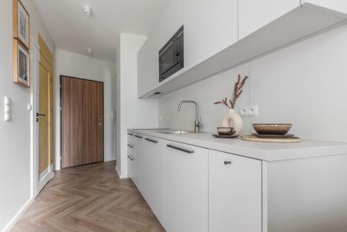 a kitchen with white cabinets and a sink at Glow Apartments, Aparthotel Kołłątaja - Wrzeszcz in Gdańsk