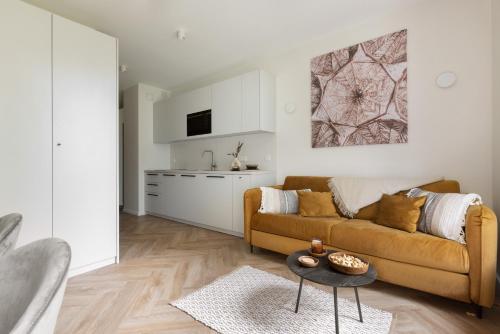 a living room with a couch and a kitchen at Glow Apartments, Aparthotel Kołłątaja - Wrzeszcz in Gdańsk