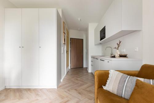 a living room with a couch and a kitchen at Glow Apartments, Aparthotel Kołłątaja - Wrzeszcz in Gdańsk