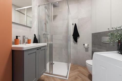a bathroom with a shower and a sink and a toilet at Glow Apartments, Aparthotel Kołłątaja - Wrzeszcz in Gdańsk