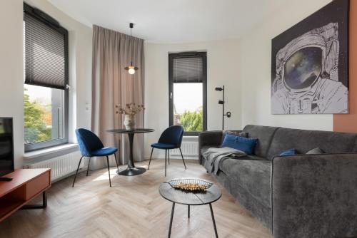 a living room with a gray couch and blue chairs at Glow Apartments, Aparthotel Kołłątaja - Wrzeszcz in Gdańsk