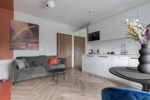 a kitchen and living room with a couch and a table at Glow Apartments, Aparthotel Kołłątaja - Wrzeszcz in Gdańsk