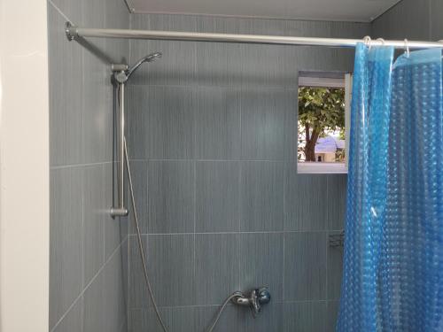 a shower with a blue shower curtain in a bathroom at Homelike Inn in Makhinjauri