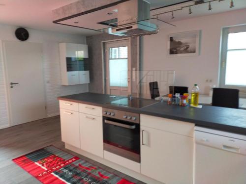 a kitchen with white cabinets and a black counter top at Exklusive FeWo Papenburg mit Terrasse & beheiztem Wintergarten in Papenburg