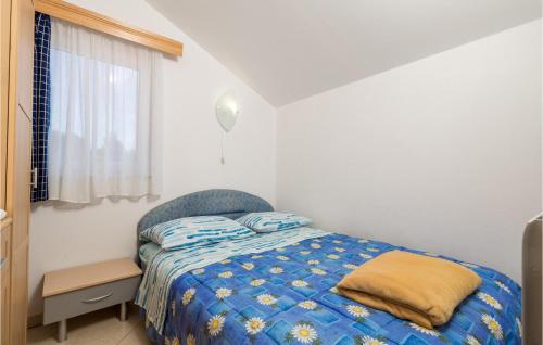 a bedroom with a bed with a blue comforter and a window at 2 Bedroom Lovely Apartment In Punta Kriza in Punta Križa