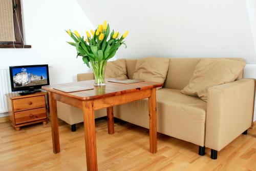 a vase of flowers on a table next to a couch at Podlesice 38 in Kroczyce