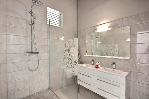 Un baño con ducha, lavabo y espejo. en Villa Eldorado, en Sainte-Anne