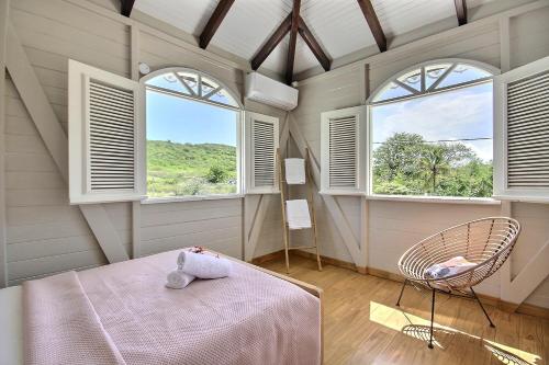 Un dormitorio con una cama y dos ventanas. en Villa Eldorado, en Sainte-Anne