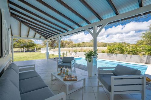 Un patio con sofás y una piscina. en Villa Eldorado, en Sainte-Anne
