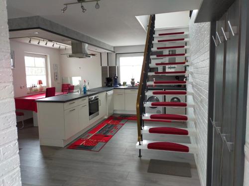 a kitchen with a spiral staircase with red accents at Exklusive FeWo Papenburg mit Terrasse & beheiztem Wintergarten in Papenburg