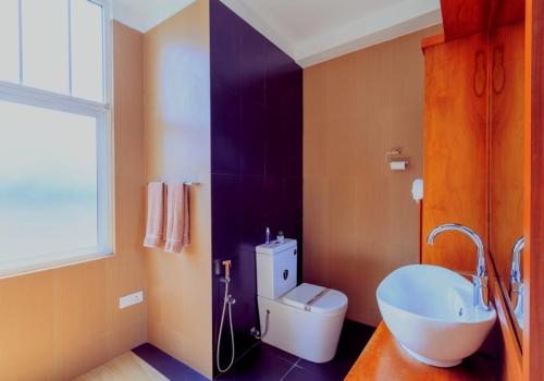 a bathroom with a white toilet and a sink at Oak Residencies in Kiribathgoda