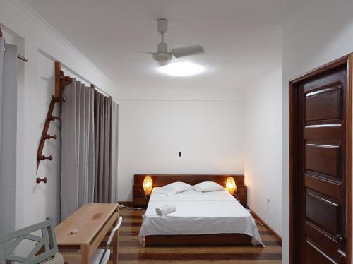 um quarto branco com uma cama e uma secretária em Residencial Brigada em Santo António