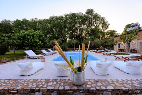 a patio with white chairs and a swimming pool at Natura Bungalows-Villa in Limenas