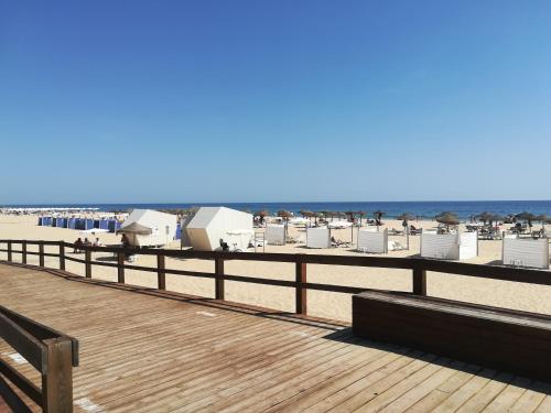 a boardwalk on the beach with beach chairs and the ocean at Maré Beach in Monte Gordo