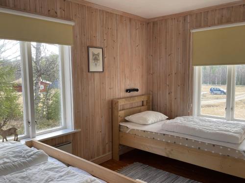 two beds in a room with two windows at Dalsvallen in Sveg