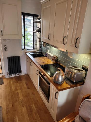 cocina con armarios blancos y fogones en LITTLE HAVEN 1 Bedroom House sought after area, en Topsham