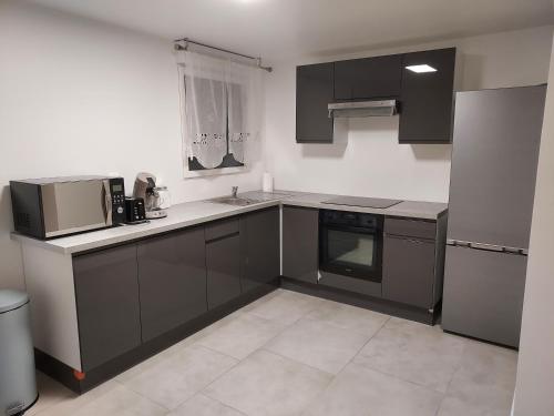 eine Küche mit schwarzen und weißen Schränken und Geräten in der Unterkunft Appartement bleu in Saintry-sur-Seine