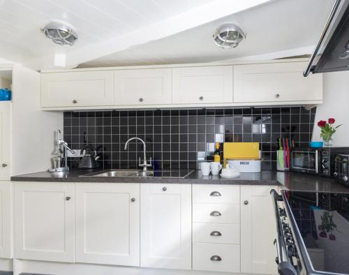 een keuken met witte kasten en een spoelbak bij Bre Cottage in Port Isaac