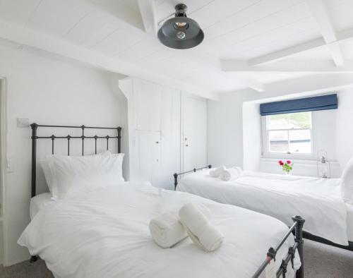 een witte slaapkamer met 2 bedden en witte kussens bij Bre Cottage in Port Isaac