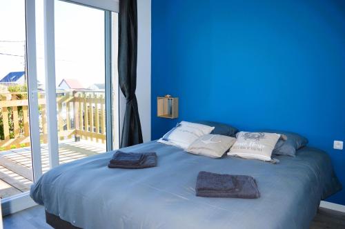 ein blaues Schlafzimmer mit einem Bett mit zwei Handtüchern darauf in der Unterkunft La maison penchée, avec jardin à 50m de la plage in Asnelles