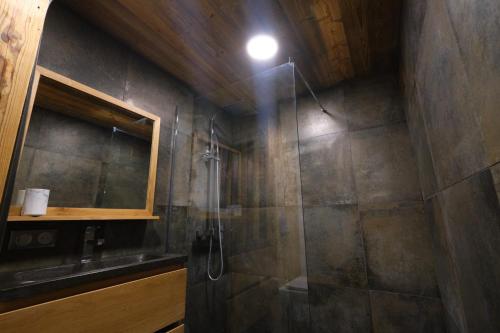 une salle de bain avec une douche avec un lavabo et un miroir dans l'établissement Au coeur du village, à Combloux