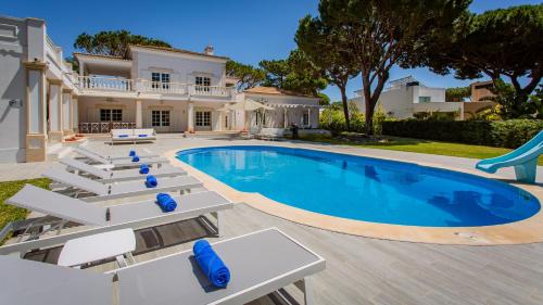 a swimming pool with lounge chairs and a house at Portuguese mansion close to marina, golf and beach. in Vilamoura