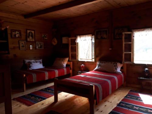 two beds in a room with wooden floors and windows at Household Babovic - Old house Miljan's valley in Andrijevica