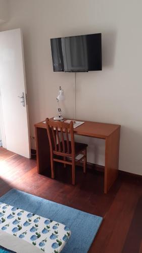 a desk with a chair and a television on a wall at City's Heart Guesthouse in Ponta Delgada
