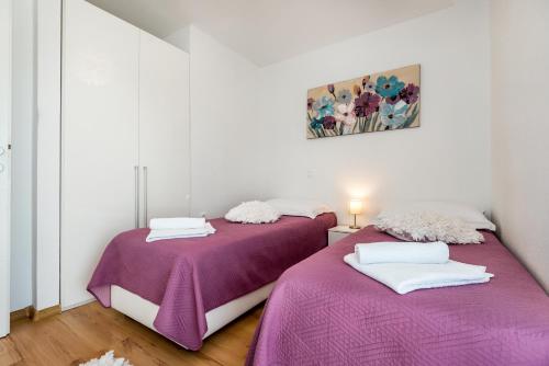 two beds in a room with purple and white sheets at Kuća za odmor - Šibenik in Brodarica