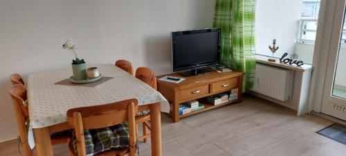 uma sala de estar com uma mesa e uma televisão em MEERBLICK PERLE, 3-RAUM-FEWO AM HANSAPARK em Sierksdorf