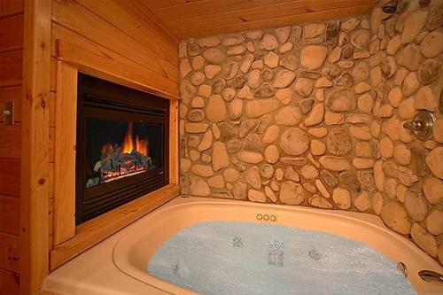 a bath tub in a room with a fireplace at Mountain Joy in Gatlinburg