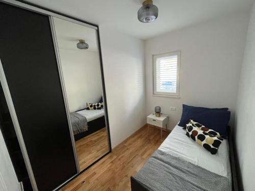 Dormitorio pequeño con espejo y cama en Apartman J&M en Makarska