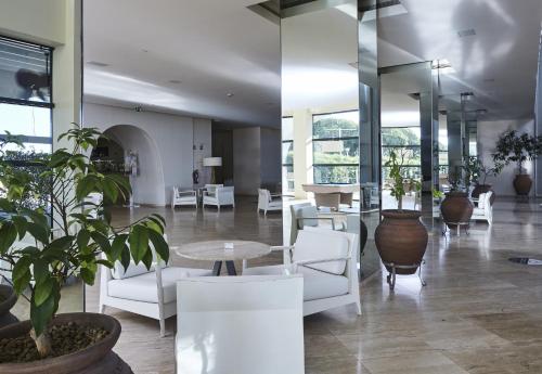 a lobby with white chairs and tables and plants at Crowne Plaza Vilamoura - Algarve by IHG in Vilamoura