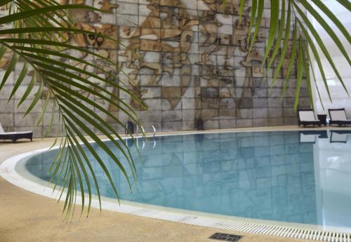 a swimming pool with two chairs and a stone wall at Crowne Plaza Vilamoura - Algarve by IHG in Vilamoura
